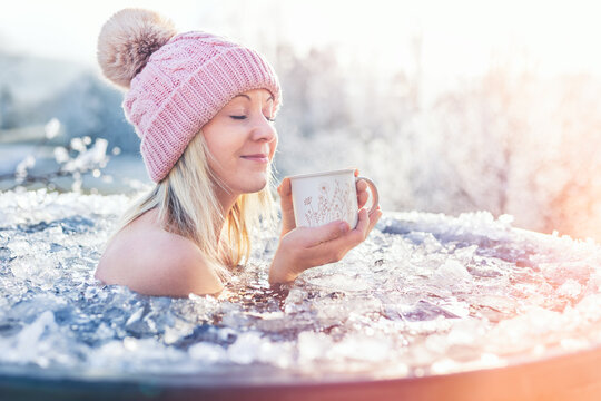 A blonde girl enjoys ice bathing during sunny frozen day, embodying strength, balance, and a healthy lifestyle. This winter challenge showcases her bravery and relaxation amidst the frosty water.