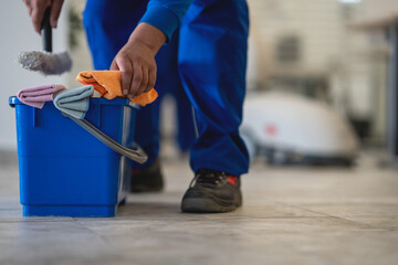 The cleaner takes the cloth from the bucket with his hand