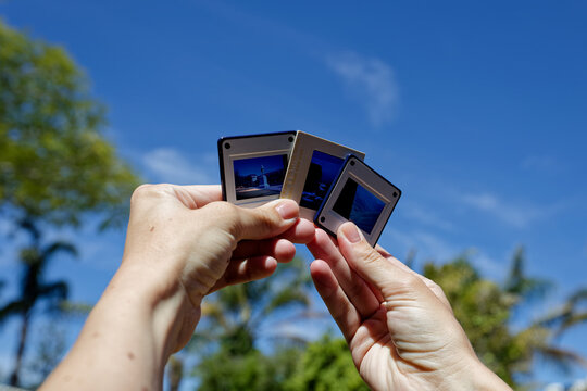 A photo of hands holding slides against the sky.
