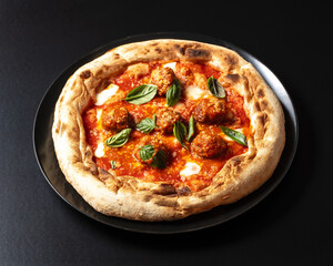 plate with meatball pizza, on black background