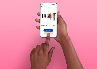 Female Shopping Concept. Above top overhead view of black woman browsing online make up store on her smart phone, isolated on pink background, touching screen. Customer ordering via internet