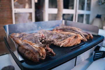 Delicious T-bone steaks grilling on a hot electric grill, releasing smoke and showing inviting cooking marks