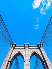 Fototapeta premium The urban architecture of New York City. A landmark in Brooklyn. The Brooklyn Bridge in New York, USA. The Brooklyn Bridge of NYC. The New York bridge linking Manhattan and Brooklyn. A route to