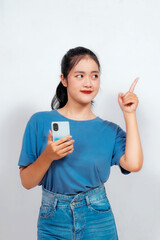 Excited Asian woman pointing at the copy space beside her, isolated on white background