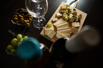 Platter of assorted cheeses with olives, pickles, and wine on a table