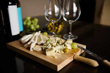 Assorted Cheese Platter with Grapes and Wine on a Wooden Board