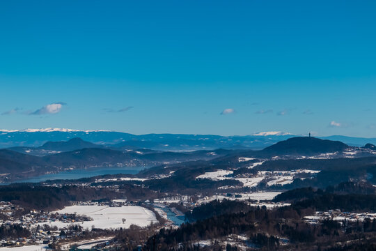 Scenic view of Pyramidenkogel and Lake Woerth in Rosental Valley seen from mount Petelin in Faak, Carinthia, Austria. Winter wonderland landscape. Austrian Alps covered in snow. Serenity and calmness