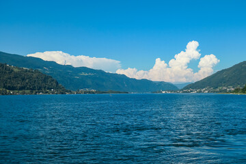 Picturesque lakeside scene with Ossiach Abbey nestled amidst lush green rolling hills in Carinhtia, Austria. Panoramic boat tour on Lake Ossiach in summer. Benedictine monastery in Austrian Alps