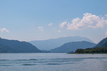 Breathtaking view of Lake Ossiach surrounded by majestic mountain Dobratsch and rolling hills of Ossiacher Tauern in Carinthia, Austria, Europe. Serene and idyllic scene in Austrian Alps in summer