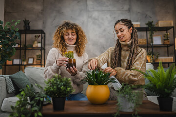 two female friends plant flowers together take care of home plants