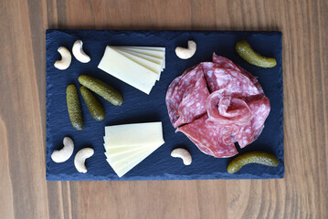 Salami and cheese on black slate board