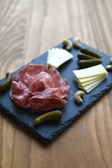 Vertical photo of salami and cheese on a black board 