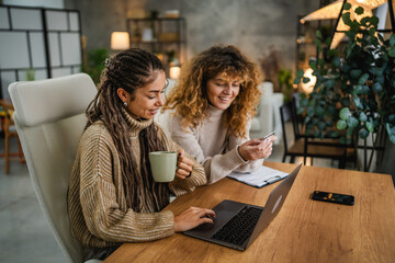 female colleagues use laptop and credit card make payments online