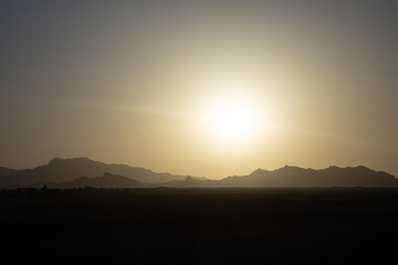 desert landscape in central iran with a bright sun and mountains in the background hot climate 