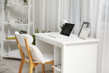 Comfortable workspace with laptop and frames in modern home office