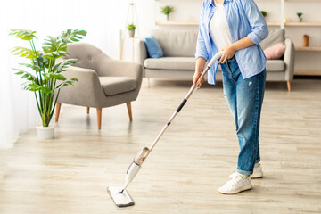 Fototapeta premium Homework Cleaning Routine. Cheerful casual lady washing hardwood laminate flooring using water spray mop pad, smiling and looking at camera. Blurred Background, Free Copy Space, Modern Interior