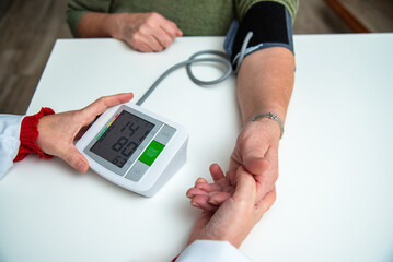 Doctor measuring blood pressure of senior woman at home visit