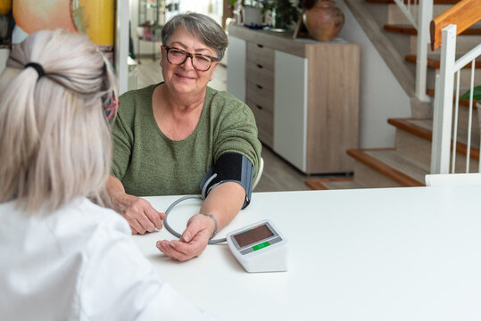 Doctor measuring blood pressure of senior woman at home