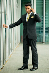 Serious, smartly dressed Asian / Middle eastern businessman holding a mobile phone to his ear, in an outdoor city location.