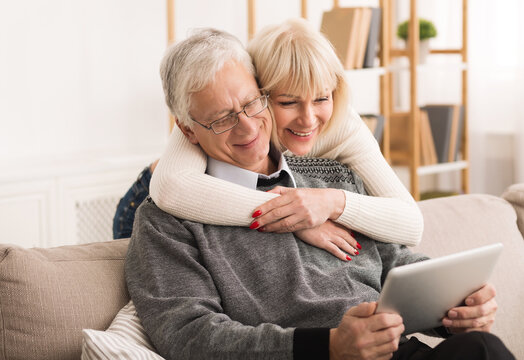 Senior couple using digital tablet, having video call in the living room