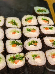 Artfully arranged sushi rolls on a wooden platter at a gathering