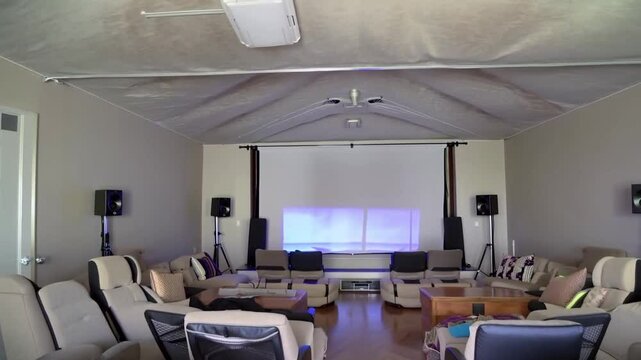 A home theater room featuring a large projector screen, surround sound speakers, and comfortable seating, creating an immersive viewing experience.