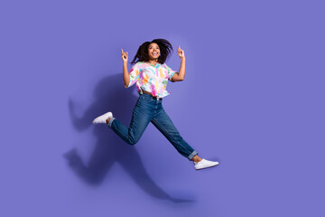 Joyful young woman jumping with excitement against a vibrant purple background, showcasing a...
