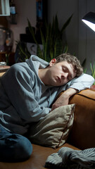 Young man asleep on a couch under lamp light, cozy interior setting, night relaxation, casual wear, peaceful home atmosphere