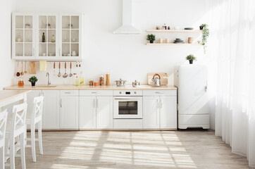 Kitchen with light walls, white furniture and shelves with crockery and plants in pots, small refrigerator in dining room scandinavian design, empty space. Modern interior with sunbeams on the floor