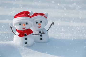 View of a couple of snowmen in a santa hats on their heads in a winter forest. Holiday christmas...