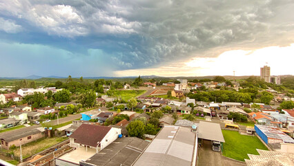 View of the arrival of a storm with strong winds, heavy clouds and torrential rain over two cities on a hot and sunny summer. Mention of climate imbalance and environmental problems.