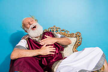 Photo of ancient happy king politician wearing traditional mantle loud laughing isolated on blue...