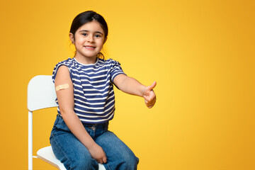 Kids Vaccination. Vaccinated Little Arab Girl Gesturing Thumb Up After Covid-19 Vaccine Injection,...