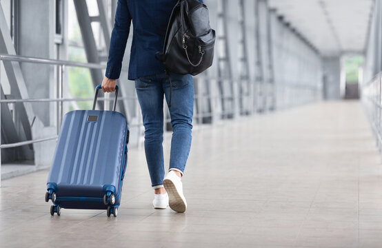 Rear View Of Unrecognizable Man Walking With Suitcase In Airport Terminal, Male Traveller Going To Flight Boarding Gate, Ready For Vacation Journey Or Business Trip, Cropped Image, Copy Space