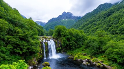 Fototapeta premium Serene waterfall cascading through lush green mountains.