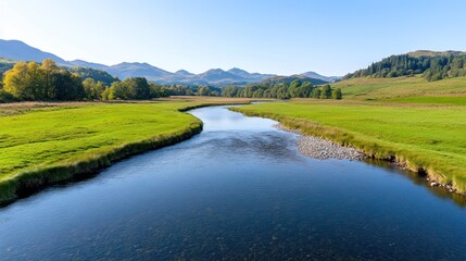 Obraz premium Serene river winding through lush green landscape under clear sky.