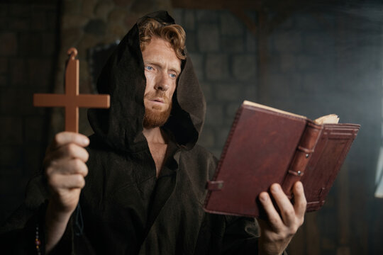 Priest holding cross and holy bible performing exorcism rite