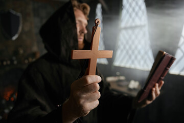 Priest holding cross and holy bible performing exorcism rite