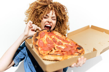 Young woman with curly hair joyfully holding a pizza box, showcasing excitement and enthusiasm for delicious food in a bright, neutral background