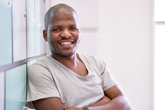 Attractive confident bald African American male with cheerful expression looking at camera in coworking space