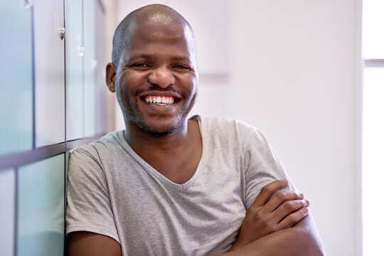 Attractive confident bald African American male with cheerful expression looking at camera in coworking space