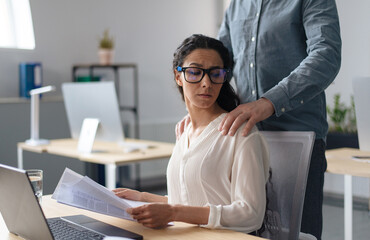 Beautiful young woman being victim of sexual harassment at workplace, copy space. Male boss...