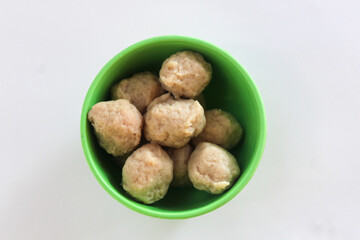 Close up of small meatballs in a green bowl, isolated on white background