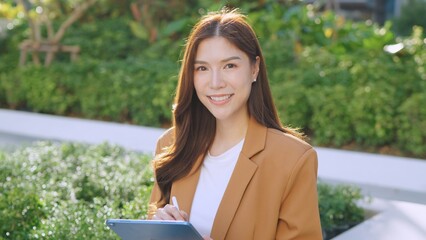 Asian Businesswoman Engaging in Outdoor Communication and Collaboration. Greenery and Growth,...