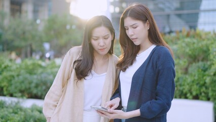 Asian Businesswomen Collaborating Outdoors: Sharing Ideas and Plans with a Tablet in an Urban Greenery Setting. Professional Asian Women Discussing Digital Marketing. Remote work online outdoors