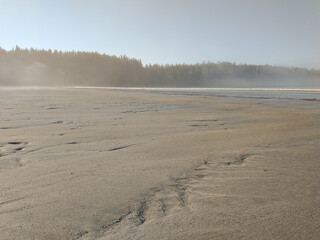 Pachena Bay Beach with misty fog rising off it during the early morning sun rise with golden sunlight illuminating 