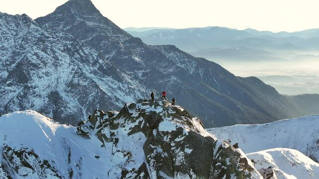 Adventurers reach the summit of a snowy mountain at sunrise in the beautiful wilderness