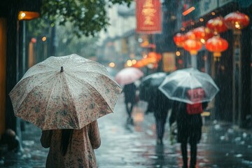 Rainy street scene; woman with umbrella, blurred pedestrians.
