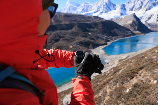 Backpacking woman checking the elevation on sports watch on high altitude mountain top