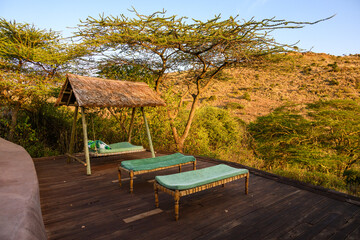 Luxury resort experience, spa deck with floating lounge beds under thatch roof with view of hillside landscape, Lewa Conservancy, Kenya, Africa
